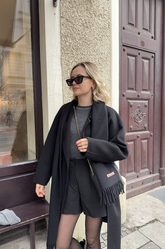 a lady in a grey top, a black wool coat and a pair of black shorts